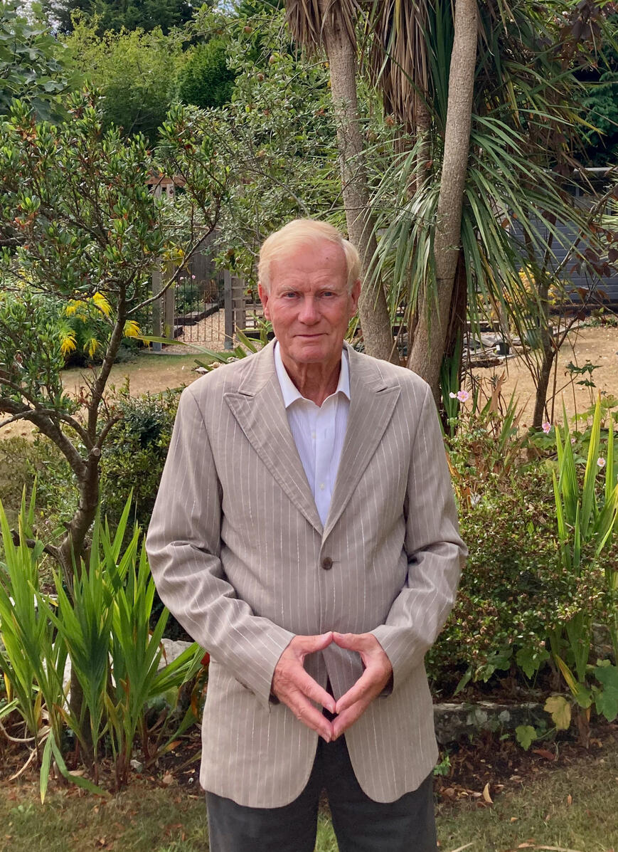 Elliot Hyland stands in front of palms and other plants